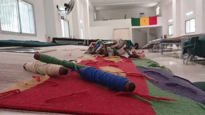 Bobines de laine posées sur une tapisserie en cours de tissage dans un atelier des Manufactures de Thiès